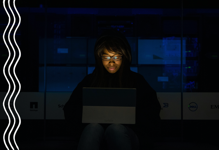 Eine Frau mit Brille sitzt im dunkeln vor ihrem Tablet, dessen Screen in ihr Gesicht leuchtet. Sie sieht konzentriert und zufrieden aus.