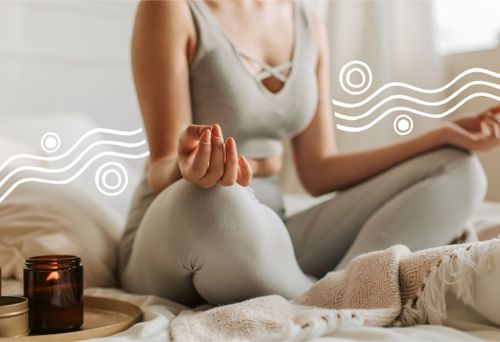 Close-Up einer Frau im Meditationssitz mit den Händen auf den Knien abgelegt, daneben eine Kerze.