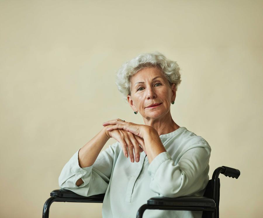 Older woman with white hair in black wheelchair, arms resting on the arm rest