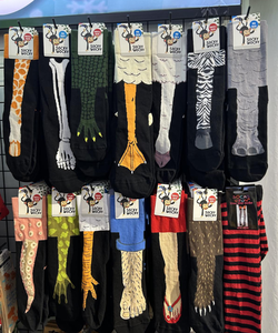 A display of animal-themed socks, featuring designs like giraffe, crocodile, duck, zebra, and more, hanging in rows on a rack.
