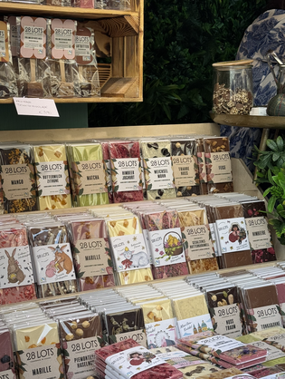 Display of assorted chocolate bars with various flavors and colorful packaging, neatly arranged on shelves at a market stall.