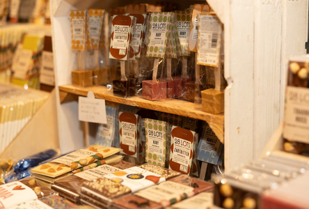 Shelves filled with assorted chocolates on display. The packaging features various colors and textures, creating a warm, inviting atmosphere.
