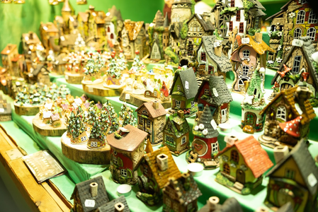 A display of miniature ceramic houses and trees on a green table, resembling a quaint village scene.