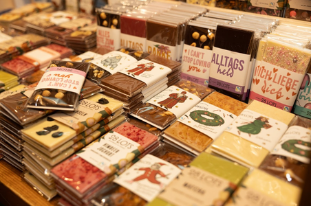 Shelves filled with assorted chocolates on display. The packaging features various colors and textures, creating a warm, inviting atmosphere.