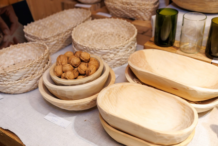 Handcrafted wooden bowls and woven baskets are displayed on a cloth-covered table. Some bowls contain walnuts, evoking a rustic, artisanal feel.