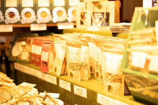 Assorted packaged food products displayed on shelves at a market, with labels and prices visible.