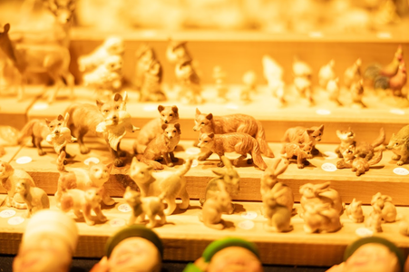 A warm-toned display of small animal figurines, including foxes and rabbits, arranged on wooden shelves. The scene is cozy and nostalgic.