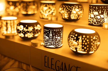 A row of illuminated candle holders with intricate city skyline cutouts, emitting warm, golden light. A label reads "Elegance," enhancing the cozy, elegant atmosphere.