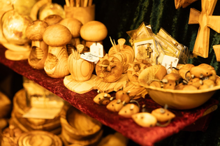 A display of handcrafted wooden items, including mushrooms, bowls, and small figurines, arranged on a red velvet surface.
