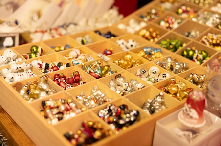 A wooden display box holds various small Christmas ornaments, including gold, silver, red, and green figures, creating a festive, cheerful vibe.
