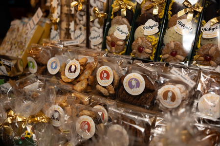 Close-up of assorted packaged holiday cookies in a market. Rows of neatly wrapped confections with ornate ribbons emit a festive, inviting vibe.