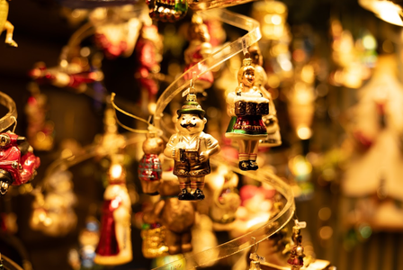 Close-up of festive glass ornaments, including a man in traditional attire, hanging on a spiral display with warm, glowing lights.