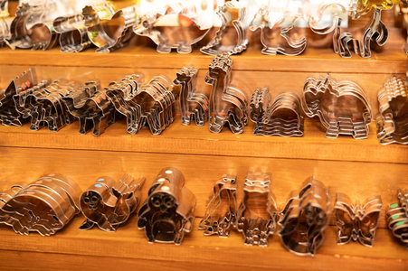 Metal cookie cutters in various animal shapes displayed on wooden shelves.