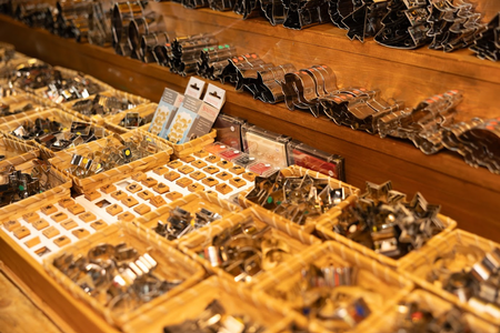 Various metal cookie cutters and small items displayed in baskets on wooden shelves in a store.
