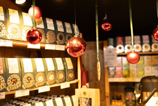 A cozy shop interior with hanging red ornaments and shelves displaying various packaged goods, warmly lit by overhead lights.