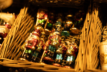 Close-up of colorful nutcracker ornaments in a wicker basket, illuminated by warm light, showcasing intricate details and festive colors.