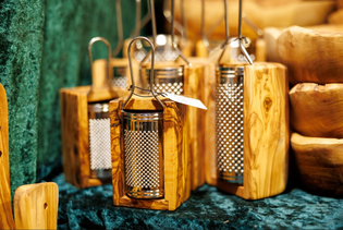 Several metal graters set in wooden holders displayed closely together on a textured dark green surface.