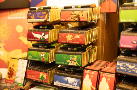 Assorted colorful chocolate bars with festive packaging displayed on shelves in a store.