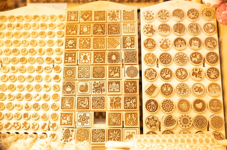 Wooden molds in various shapes and designs, including squares and circles, are displayed. They feature intricate patterns and decorative motifs.