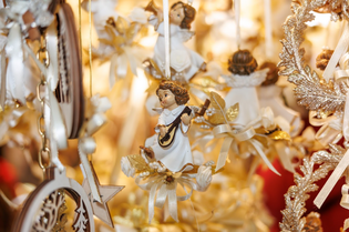 Hanging Christmas ornaments include angel figurines playing guitars, adorned with gold and white ribbons. The scene is warm and festive, evoking holiday cheer.