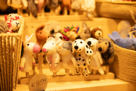 A group of felt animal finger puppets, including a unicorn, mice, Dalmatian, and dog, are displayed in baskets on a wooden shelf. Price tag reads €9.99.