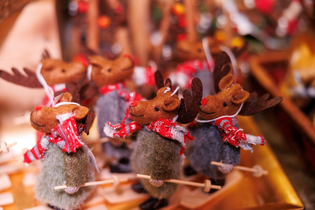 Felt reindeer ornaments wearing red scarves, standing in rows on a wooden surface. They hold tiny skis, exuding a festive, cheerful atmosphere.