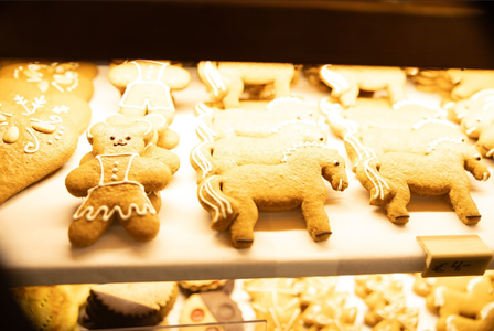Gingerbread cookies shaped like bears and horses, decorated with icing, displayed on a tray in a warmly lit bakery.