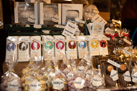 A display of assorted chocolates and sweets in bright packaging, featuring whimsical designs and labels. The warm lighting adds a cozy, festive feel.