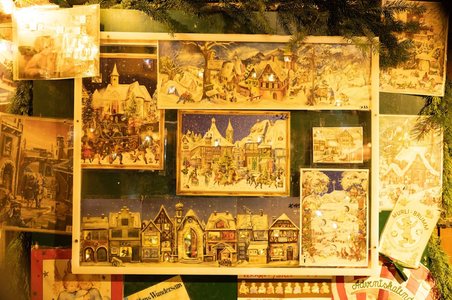 A display of vintage holiday postcards with winter scenes, surrounded by evergreen branches and warm lighting.