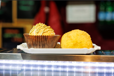 Two arancini on a tray — one savory with a golden, crispy coating, and one sweet pistachio arancino