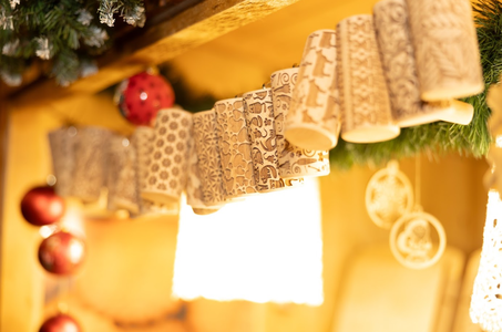 Close-up of intricately patterned rolling pins hanging on a wooden shelf, adorned with pine garlands and red ornaments, creating a festive ambiance.