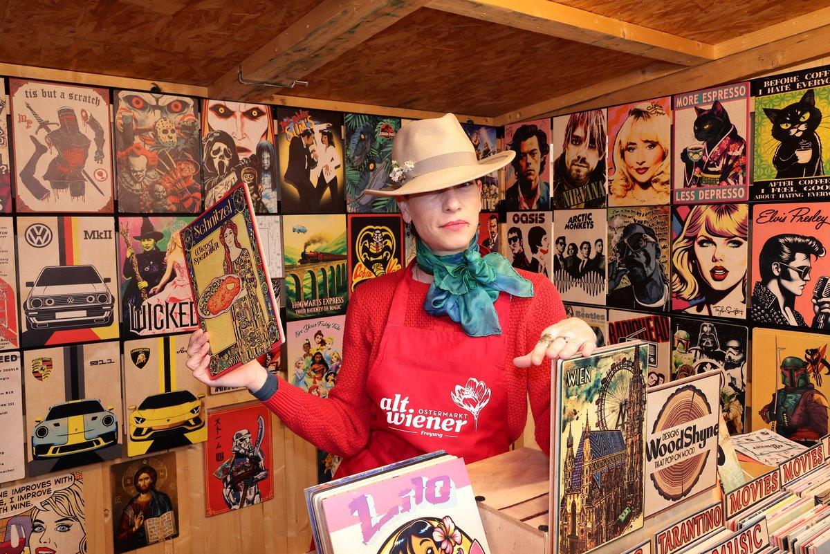 Person in a hat and scarf browsing vintage posters in a shop with colorful, retro-themed walls.