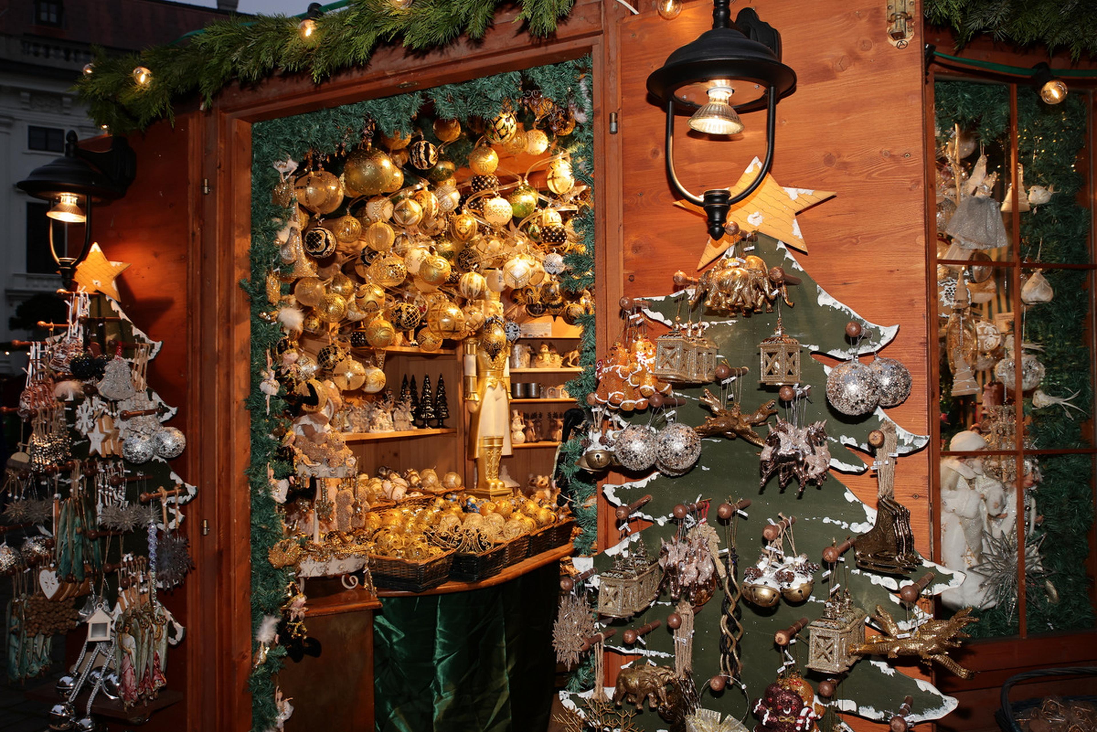 A festive market stall adorned with glowing ornaments, decorated trees, and various Christmas decorations under warm lights.