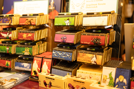 Assorted chocolate bars with colorful packaging displayed on shelves at a market stall.