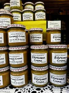Jars of caramel and lemon cream are stacked on a lace-covered surface, with labels in German.
