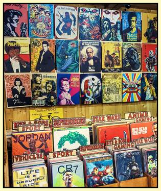 A display of various colorful posters featuring movies, superheroes, sports, and anime, accented by a wooden backdrop.