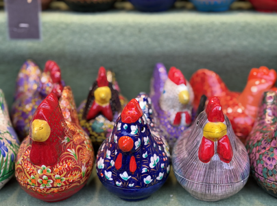 Colorful ceramic chickens with intricate patterns displayed on a shelf, showcasing a variety of vibrant designs and floral motifs.