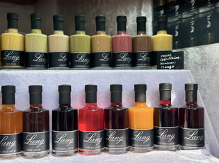 A display of variously colored liqueur bottles arranged in rows, each labeled 'Lang' with flavors visible in different colored liquids.
