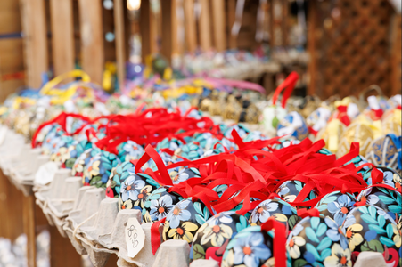 Colorful decorative eggs with floral patterns and red ribbons displayed on cardboard trays in a market setting.