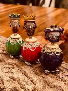 Three ornate, king-themed bottle stoppers with colorful robes and crowns, standing on a wooden surface.