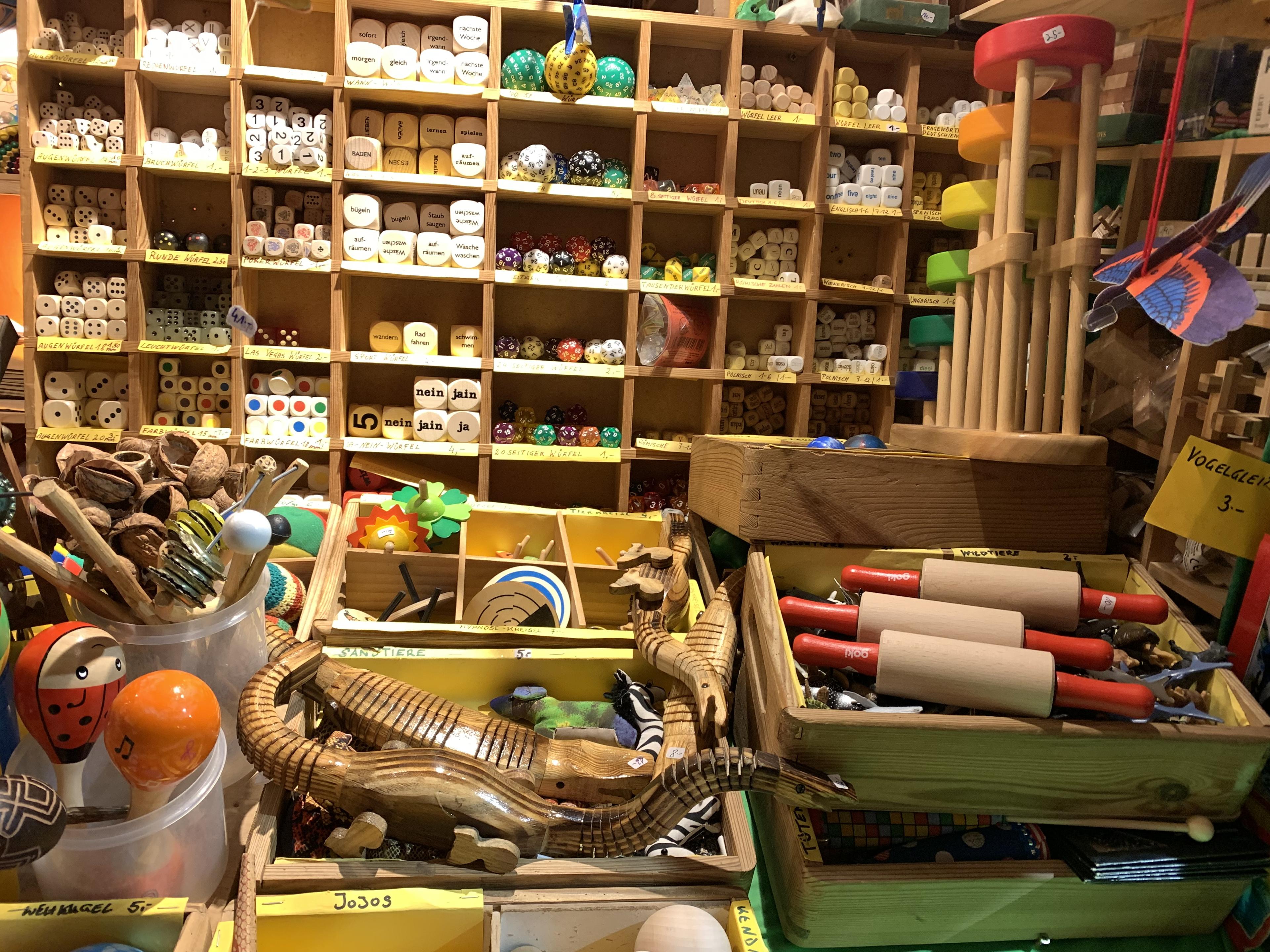 A colorful shop display with wooden toys, dice, and games neatly arranged in cubbies and bins. Bright and inviting atmosphere.
