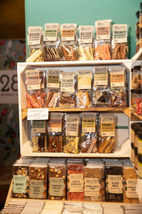 Shelf displaying various chocolate bars in clear packaging, labeled with different flavors like strawberry, caramel, and mocha. Warm, inviting ambiance.