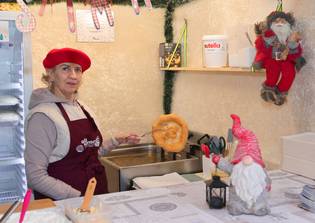 a woman holding a langos in a christmas market booth