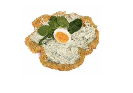 A crispy base topped with creamy spinach sauce, a slice of boiled egg, and fresh spinach leaves on a white background.