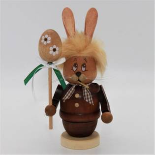Wooden rabbit figurine with a fluffy mane, holding a decorated egg on a stick with ribbons.