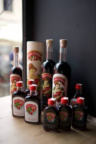 Various bottles of cherry liqueur with labels featuring a woman holding cherries, displayed on a wooden surface against a dark background.