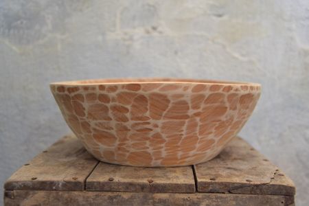 A ceramic bowl with a textured, giraffe-like pattern on a wooden surface against a light gray background.