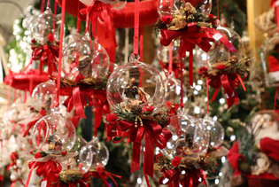 Glass ornaments with red ribbons and festive decorations hang, displaying small nativity scenes inside.