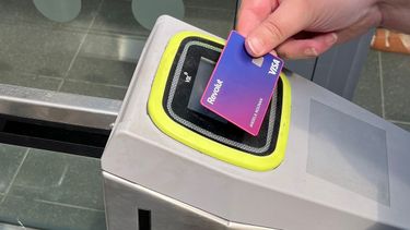 Someone tapping in on a contactless rail card reader.