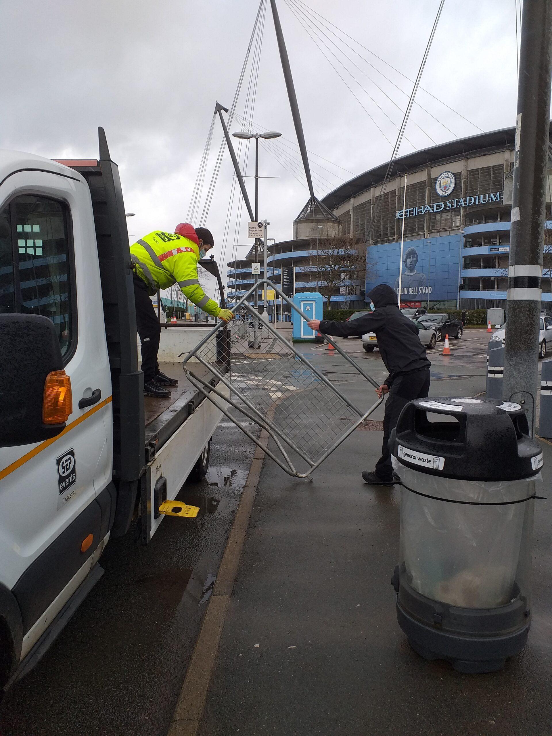 Workmen unloading fencing from a flat back truck.